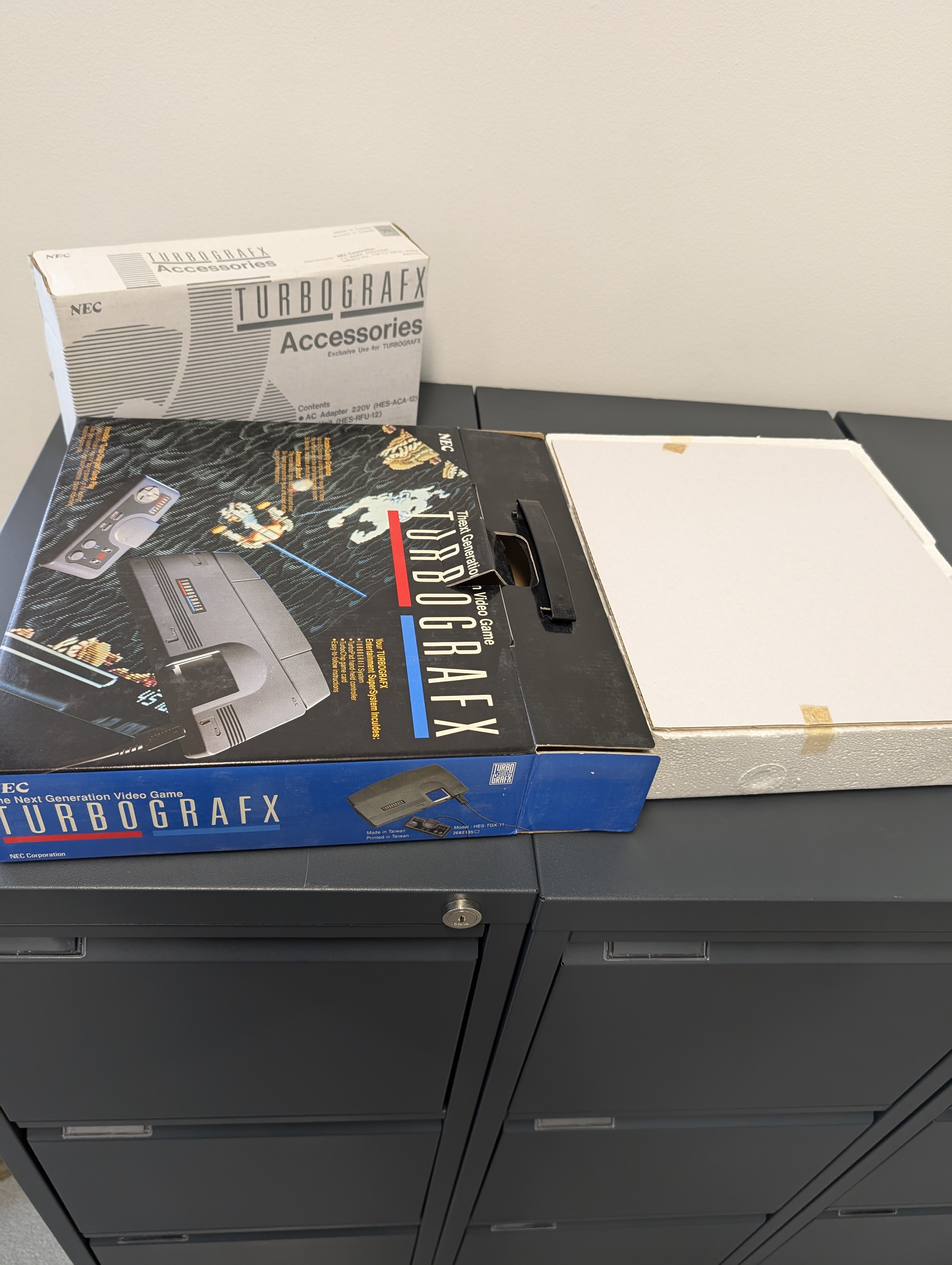Pudełka NEC TurboGrafx-16 i akcesoriów rozłożone na szafce
