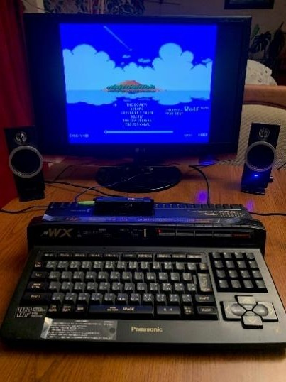 Komputer MSX z monitorem wyświetlającym grę i głośnikami
