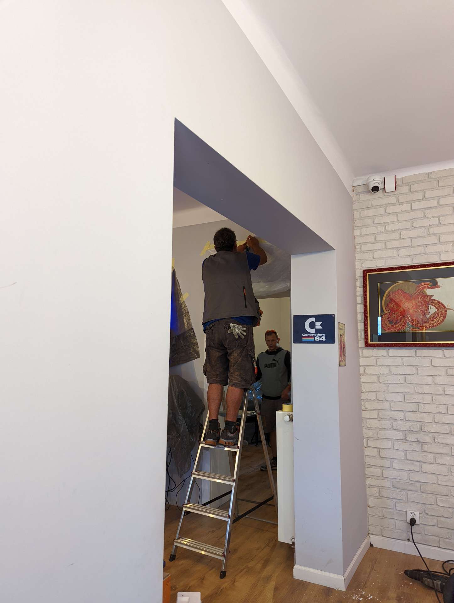 Instalator na drabinie w drzwiach z logo SMOK