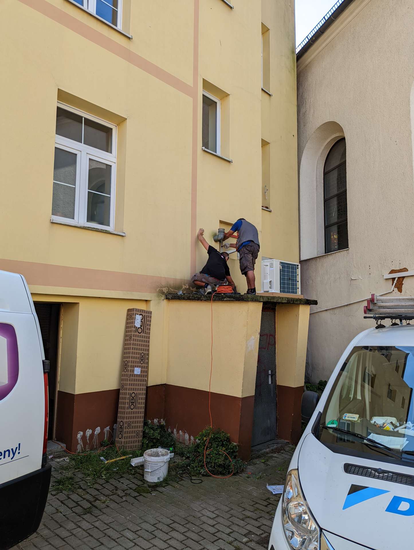 Instalator przy ścianie budynku podczas montażu
