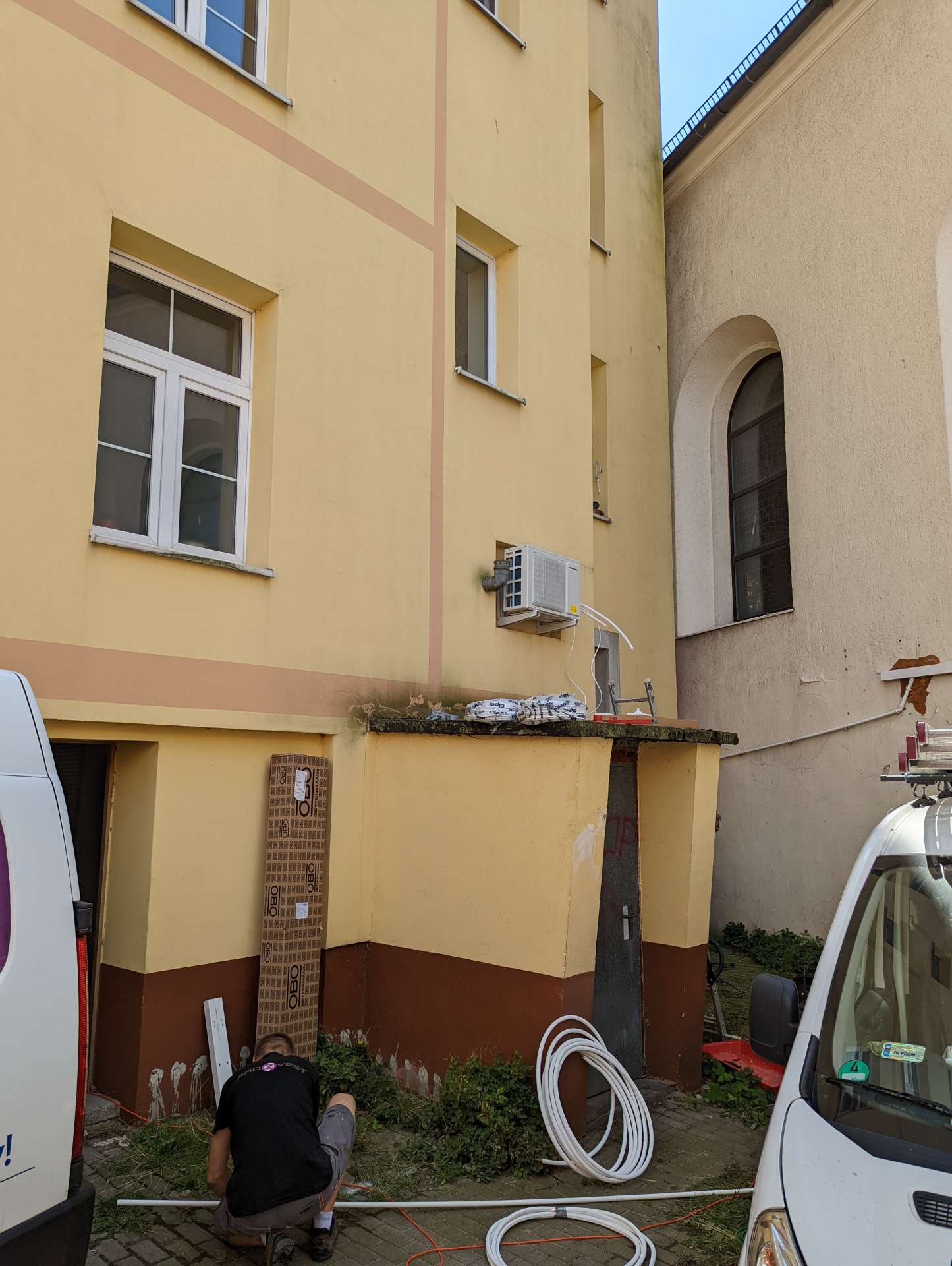 Instalator i firmowy van przy elewacji budynku